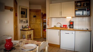 Una cucina compatta con mobili bianchi, una macchina da caffè e un'lavastoviglie.