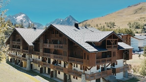 Una baita di legno con diversi balconi, sullo sfondo montagne.