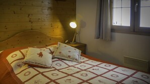 Una stanza con rivestimento in legno, un letto, una lampada da comodino e una finestra.