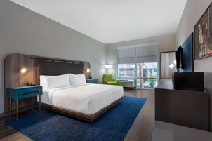 Una habitación de hotel moderna con una cama grande, un escritorio, una silla y un televisor.