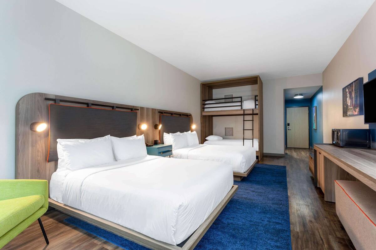 Habitación de hotel con dos camas, un escritorio, un televisor y una litera.