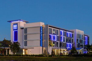 A modern hotel with a prominent 'TRYP' sign, multiple floors, and blue lighting accents.