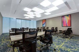Una sala conferenze con un lungo tavolo, diverse sedie e ampie finestre.
