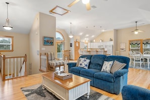 A spacious living room with a blue sofa, wooden coffee table, and a view of the kitchen and dining area.