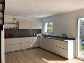Cozinha moderna com armários brancos, bancada preta e janela que oferece luz natural.