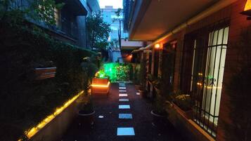 A narrow pathway with stepping stones leading to a brightly lit area with a green light.