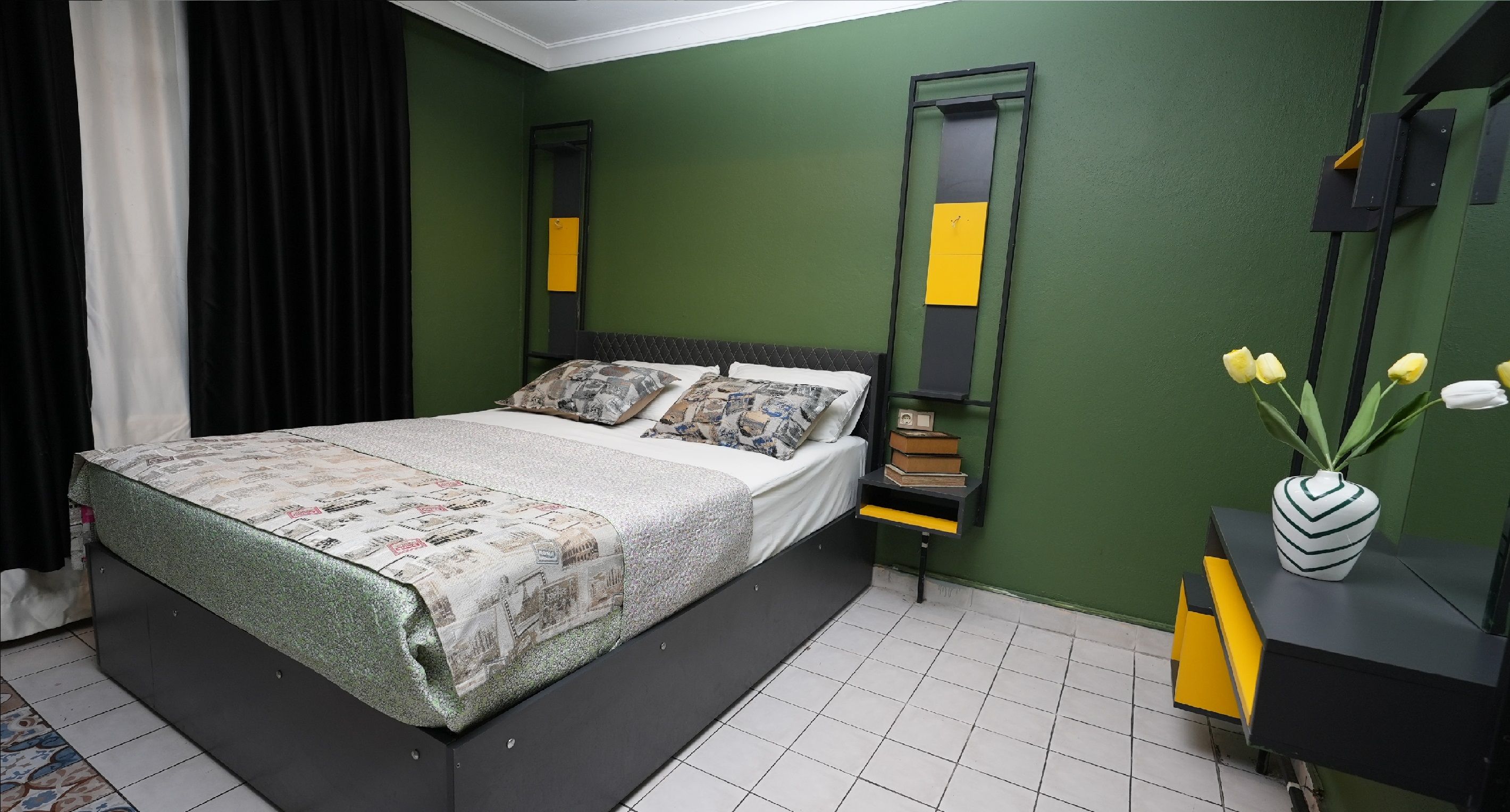 A bedroom with a bed, a nightstand, a mirror, and a vase with flowers.