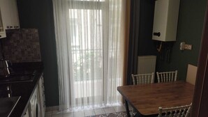 A kitchen with a stove, washing machine, and a dining table with chairs. - Butik 24 Suites (Ankara)