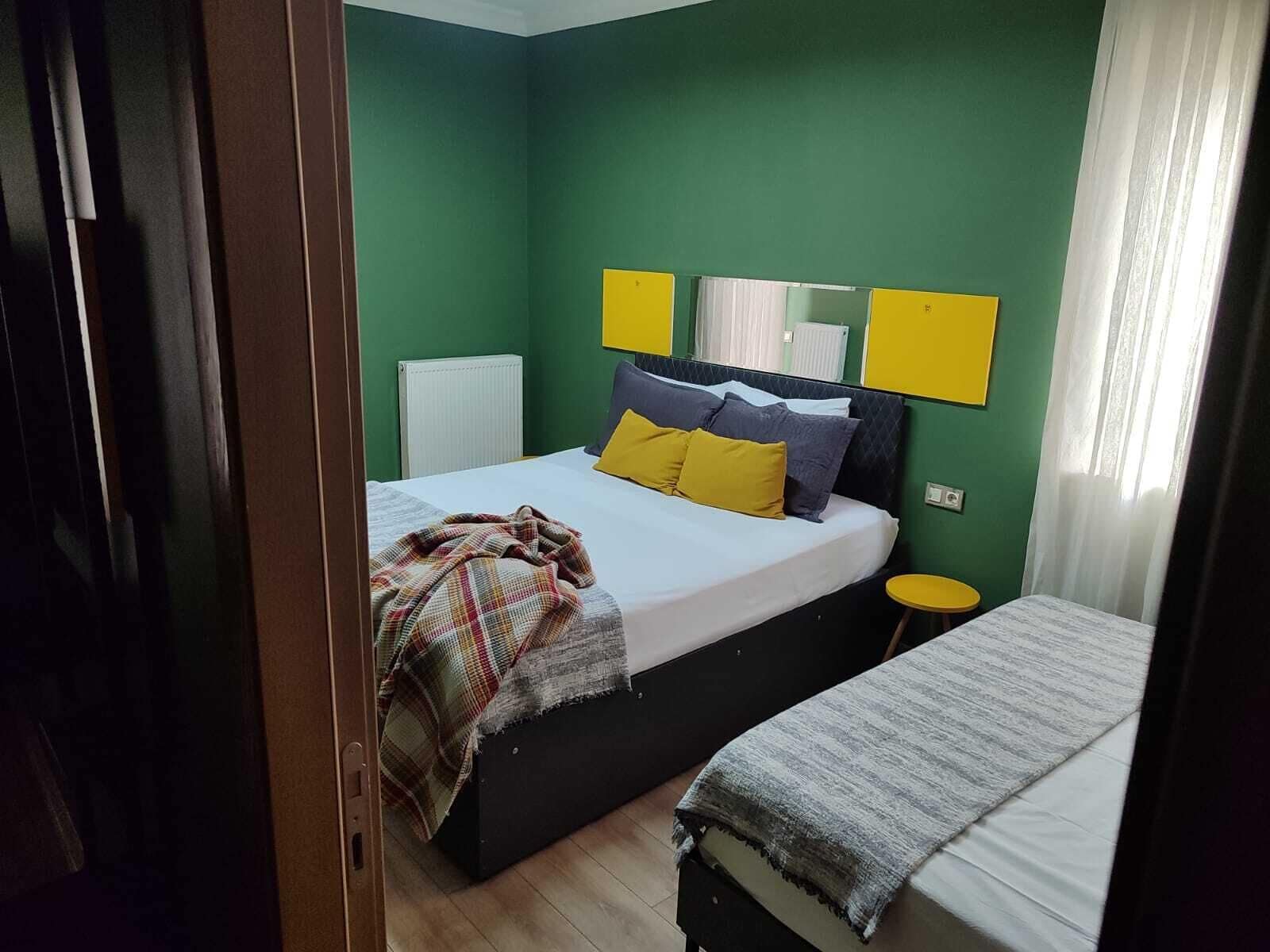 Una camera da letto con un letto, un comodino, un termosifone e una finestra con tende.
