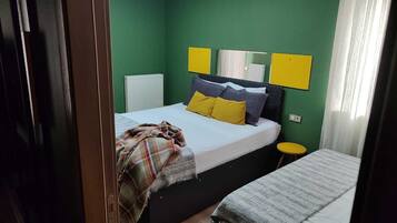 Una camera da letto con un letto, un comodino, un termosifone e una finestra con tende.