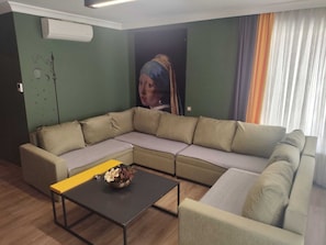 A living room with a sectional sofa, a coffee table, and a wall-mounted air conditioner. - Butik 24 Suites (Ankara)