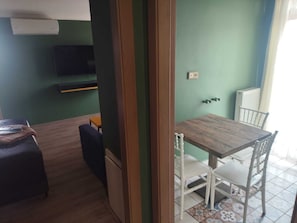 A room with a wooden dining table, white chairs, a small sofa, and a television on the wall. - Butik 24 Suites (Ankara)