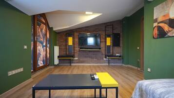 A room with a brick fireplace, a flat-screen TV mounted on the wall, and a large window.