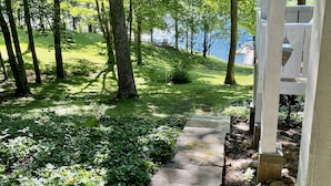 Un sentier de pierres qui traverse une zone verdoyante, bordée d’arbres, et offre une vue sur un lac.