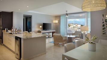 A modern kitchen with a built-in island, a dining area with a table and chairs, a TV, and a balcony with a view.