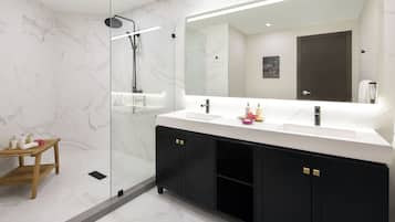Un baño moderno con ducha de vidrio, un espejo grande y un tocador con muebles de negro.