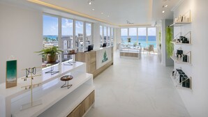 Un moderno vestíbulo de hotel con un amplio ventanal que ofrece vistas al mar, una recepción y una zona de estar con vistas.