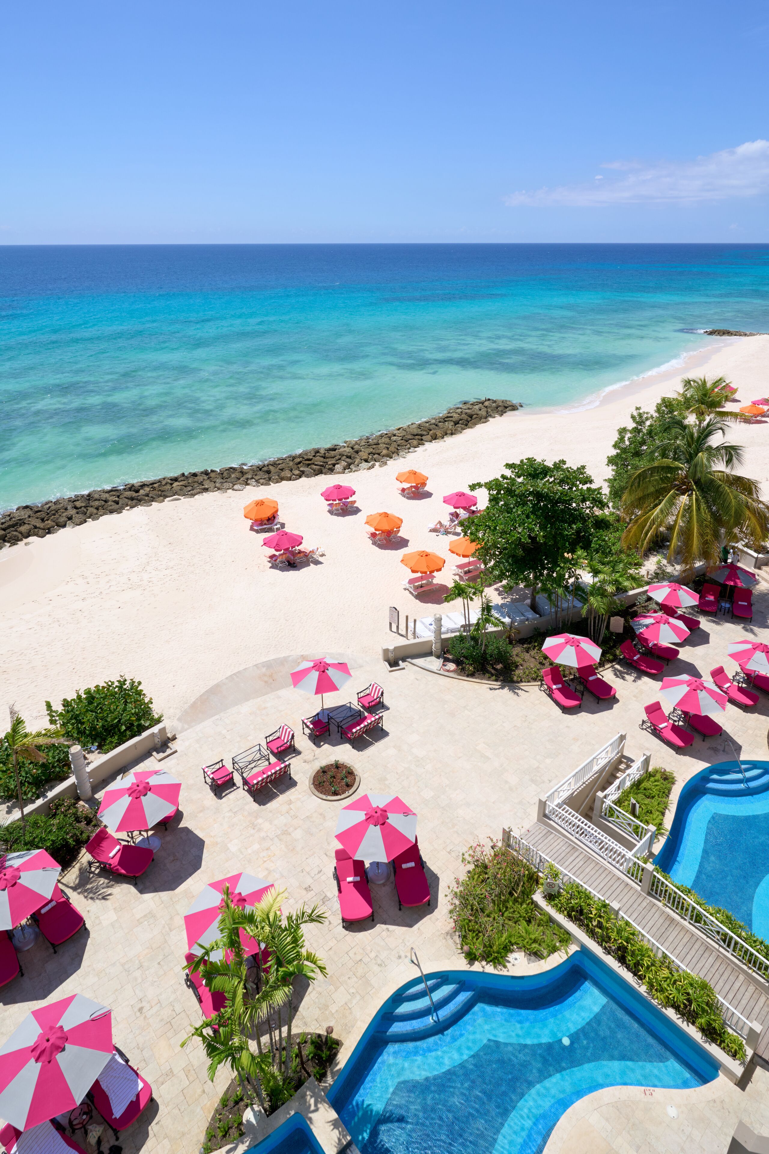 Un complexe hôtelier doté d’une piscine, de chaises longues et de parasols sur la plage.