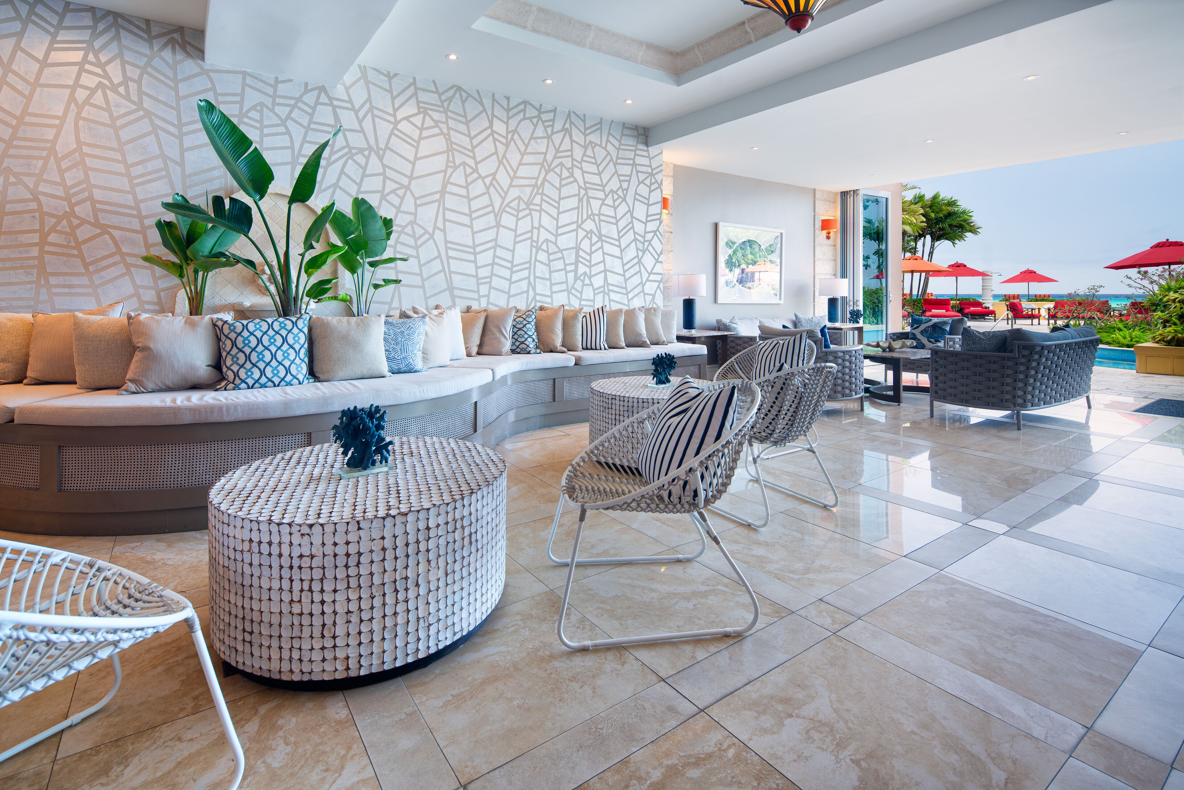 A modern lounge area with a seating arrangement, a patterned wall, and a view of the beach.