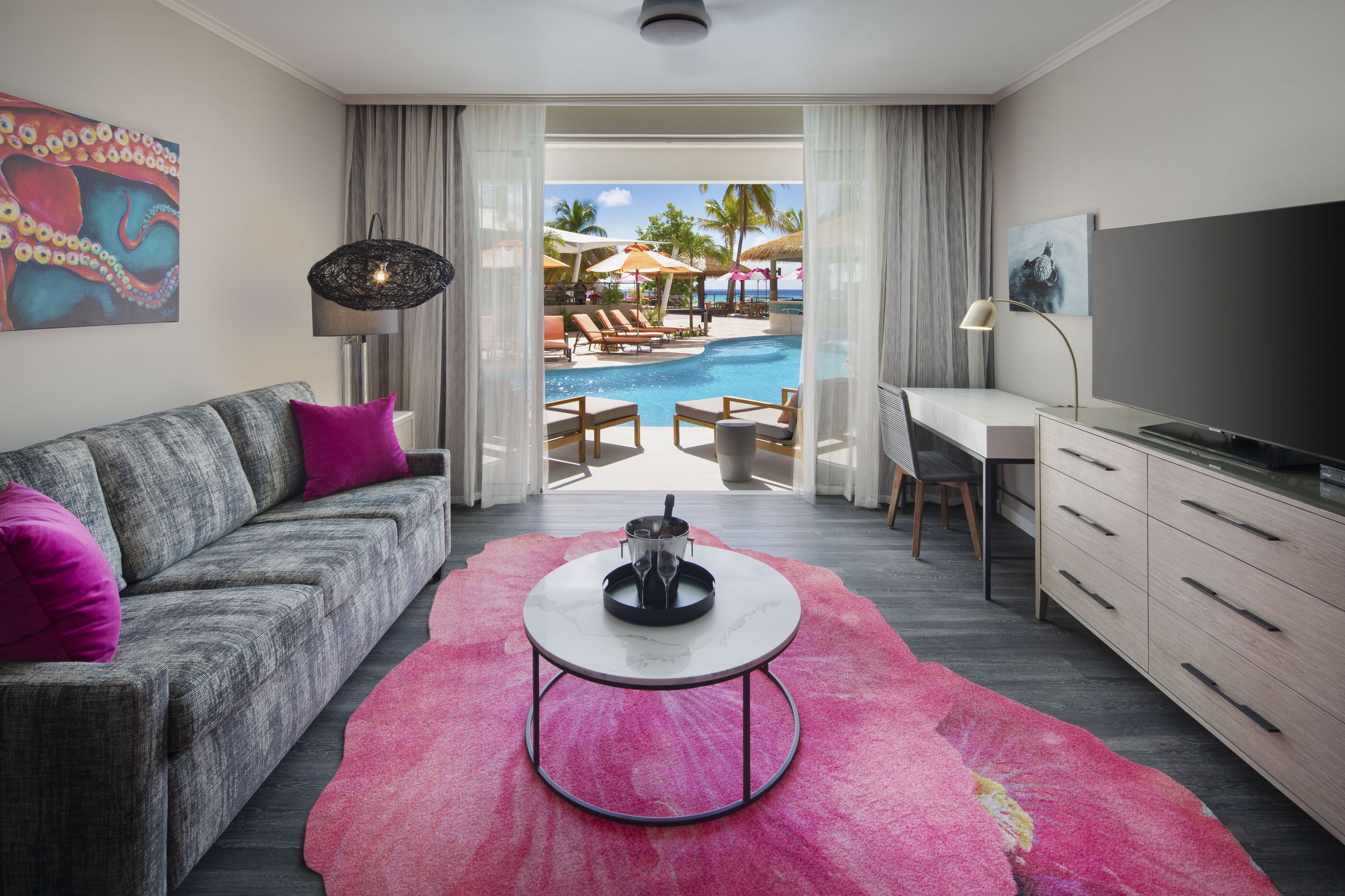 A modern living room with a pool view, a sofa, a coffee table, and a TV.