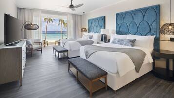 Habitación de hotel con una cama grande, un escritorio, un televisor y vista a la playa.