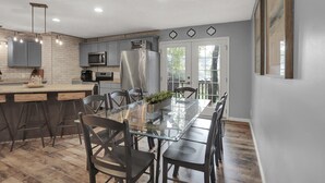 A modern kitchen with a central island, grey cabinets, and a large window.