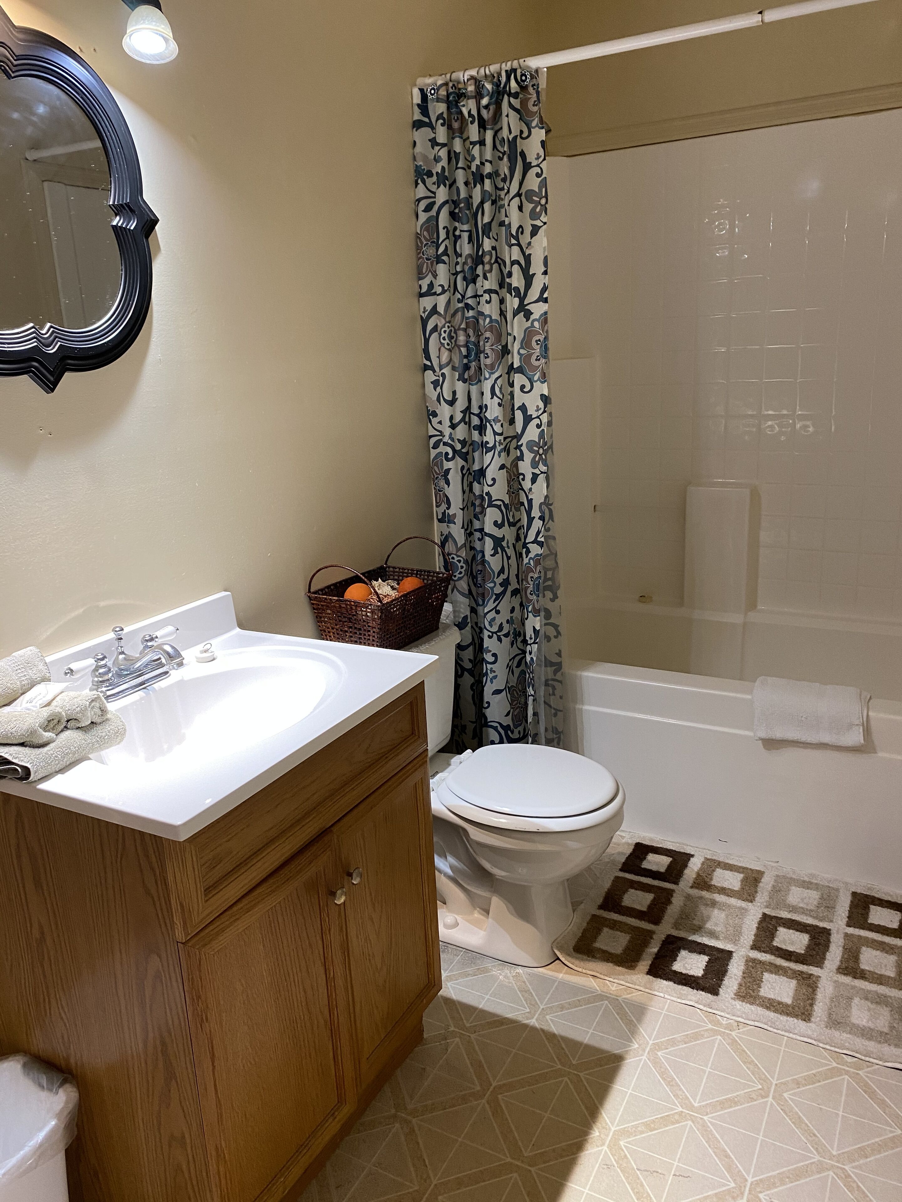 Un baño con lavamanos blanco, tocador de madera, inodoro, cortina de ducha y bañera.