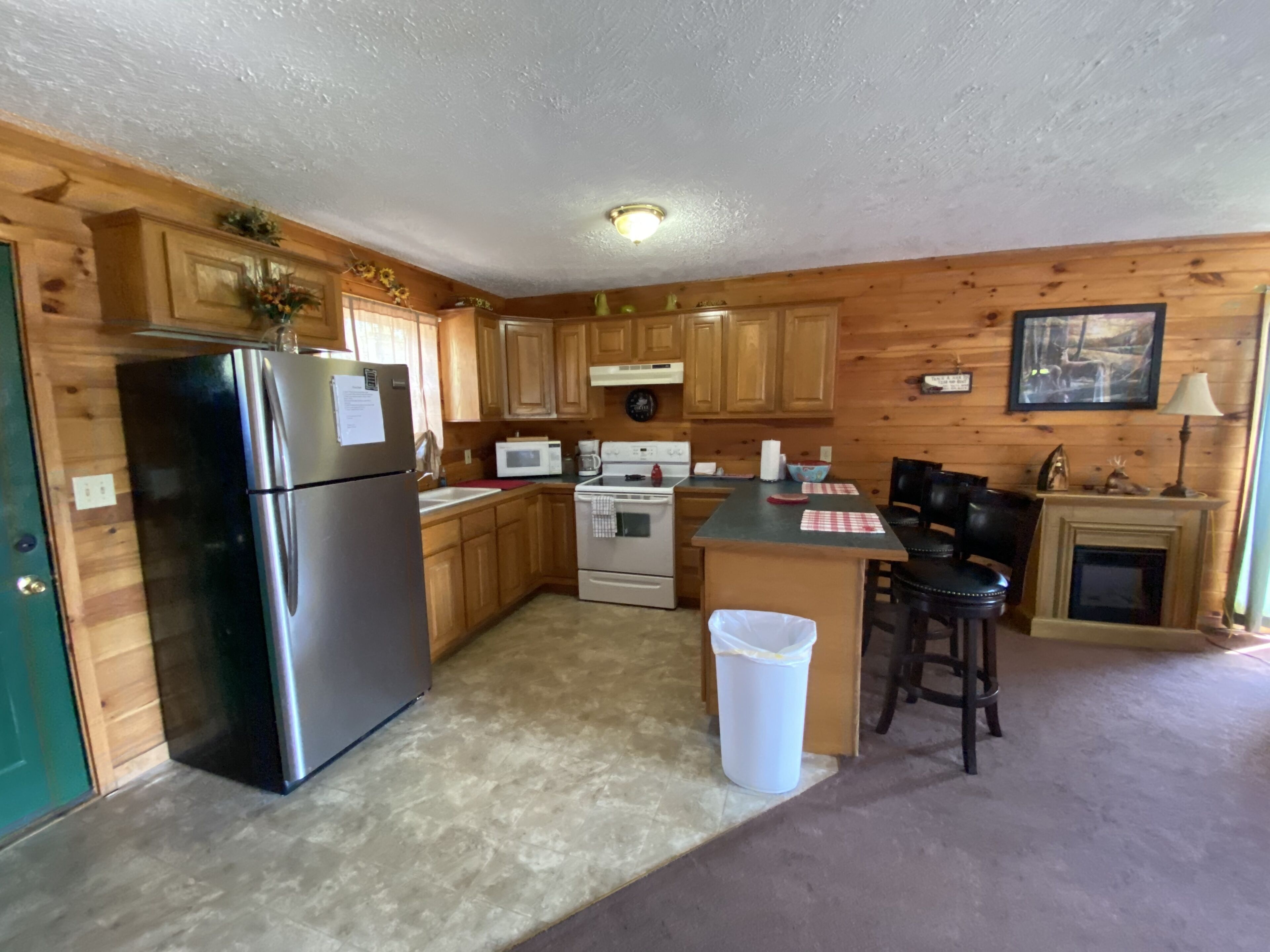 A kitchen with wooden cabinets, a stainless steel refrigerator, a microwave, and a stove.