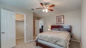 A bedroom with a bed, a ceiling fan, a door, and a hallway. - Corporate, Lackland, Sea World, Alamo, Fiesta, Riverwalk BMT graduation (San Antonio)