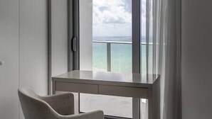A modern room with a large window overlooking a balcony and the sea.