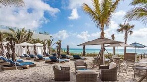 A beach with lounge chairs, umbrellas, and wicker furniture.