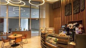 A modern cafe with a wooden interior, a counter with a display case, and a seating area with a round table and chairs.
