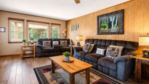 A living room with two sofas, a wooden coffee table, and a ceiling fan.