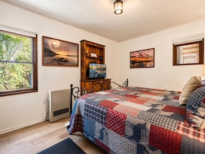 Ein Schlafzimmer mit einem Bett, einem Holzkabinett und zwei Bildern an der Wand.