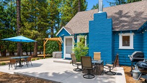 A blue house with a patio, outdoor seating, and a grill. - Bear Slope View - Close to Slopes, Pet Friendly, Fenced Yard, Hot Tub (Big Bear Lake)