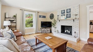 Een woonkamer met een open haard, een televisie en een bank.