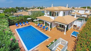 A poolside area with a swimming pool, lounge chairs, and a barbecue area. - Villa White Sands - Private Oasis, Heated Pool, Beaches & Strip Nearby (Albufeira)