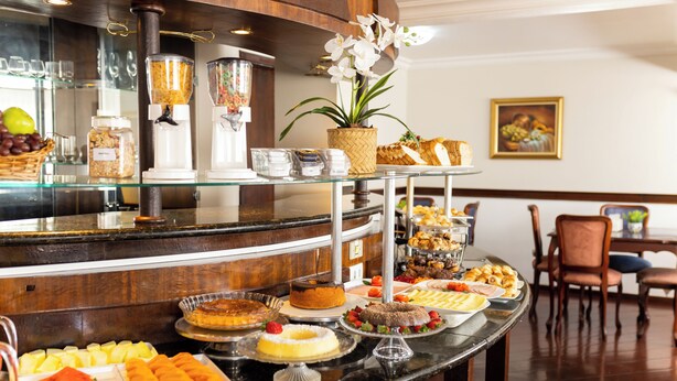 A buffet with various food items and a decorative orchid plant. - Hotel Wynn Batel (Curitiba)