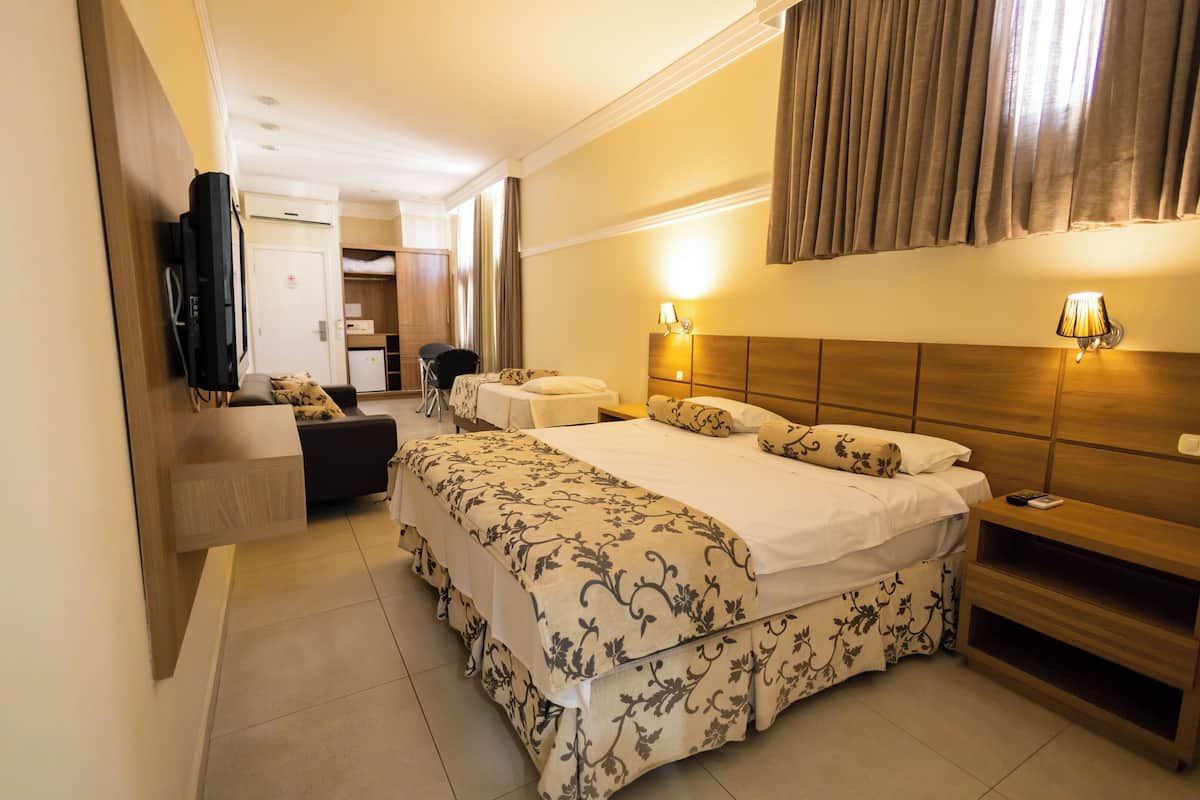 Une chambre d’hôtel avec deux lits, une télévision, un bureau et une chaise.