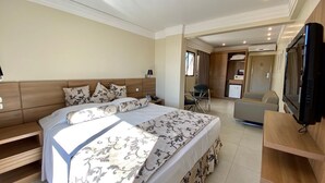 A modern hotel room with a large bed, a TV, a desk, and a seating area. - Hotel Wynn Batel (Curitiba)