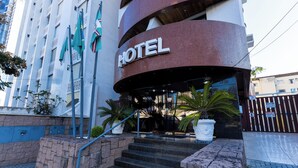 A hotel entrance with a curved facade, steps leading up to the entrance, and potted plants. - Hotel Wynn Batel (Curitiba)