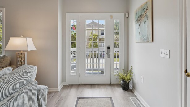 A living room with a sofa, a lamp, a potted plant, and a door leading outside. - 41 Bradley, Private Pool, Newly Updated, Close to Beach, Free Golf (Hilton Head Island)