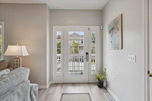 A living room with a sofa, a lamp, a potted plant, and a door leading outside. - 41 Bradley, Private Pool, Newly Updated, Close to Beach, Free Golf (Hilton Head Island)