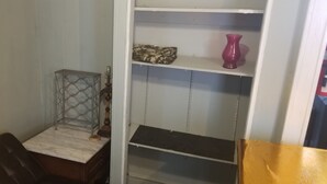 Una habitación con un escritorio de encimera de mármol, un armario metálico y una estantería con un objeto estampado de camuflaje y un florero rosa.