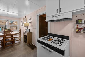 Una cucina con piano cottura bianco, mobili in legno e un'area pranzo con tavolo e sedie.
