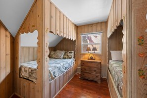 Una camera da letto in stile chalet con soffitto spiovente, pareti in legno e una finestra vista panoramica.