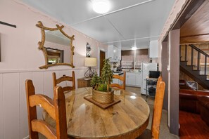 A dining area with a round table, wooden chairs, a potted plant, and a mirror on the wall.