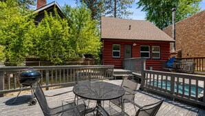 Eine Holzterrasse mit Grill, Sitzgelegenheit und Schwimmbad.