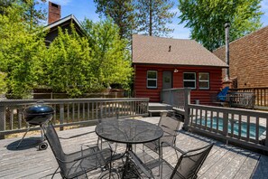 Un patio in legno con una griglia barbecue, posti a sedere all'aperto e una piscina.