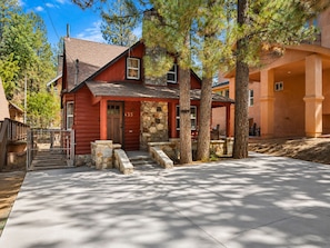 A red log cabin with a stone porch, a stone chimney, and a number 435 on the door.